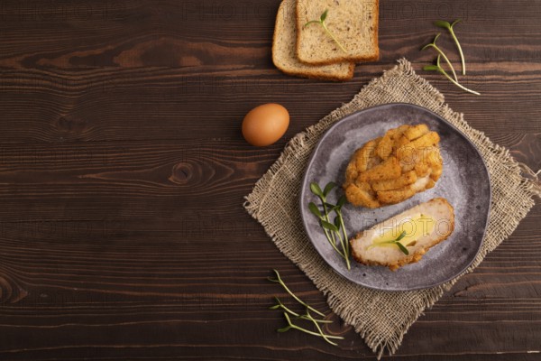 Chicken Schnitzel on gray plate with microgreen on brown wooden background and linen textile. top view, flat lay, copy space