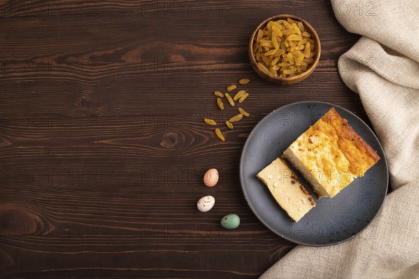 ?ottage cheese ?asserole, Curd cake, with dried apricots and raisins on brown wooden background and linen textile, top view, flat lay, copy space, minimalism