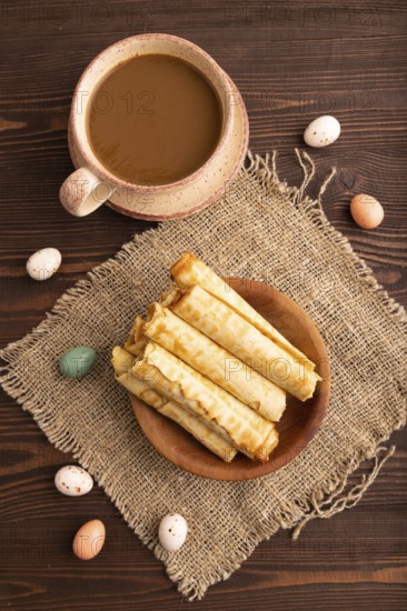 Waffles with caramel on brown wooden background and linen textile, cup of coffee, top view, flat lay, close up