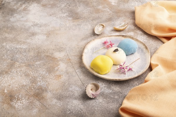 Japanese Mochi Cakes on brown concrete background and orange textile, side view, copy space
