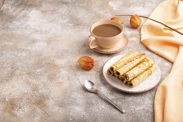Waffles with caramel on brown concrete background and orange linen textile, cup of coffee, side view, copy space
