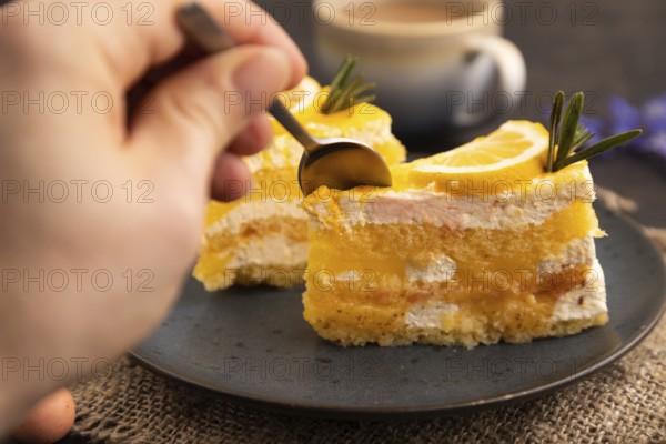 Lemon cake with hand on black concrete background and linen textile, cup of coffee, side view, close up, selective focus