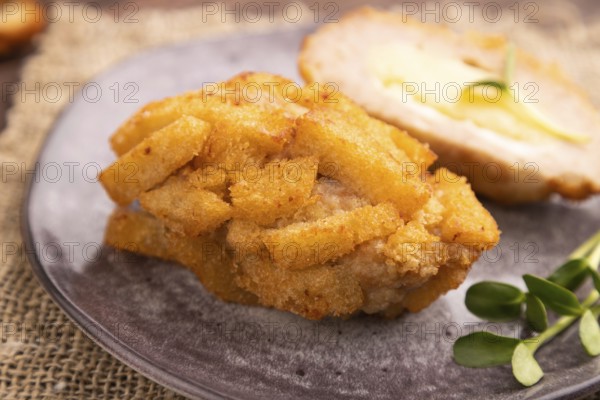 Chicken Schnitzel on gray plate with microgreen on brown wooden background and linen textile. side view, close up, selective focus