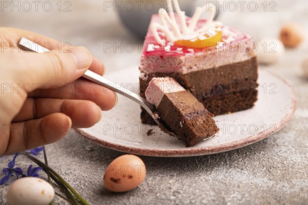 Chocolate cake with hand on brown concrete background, cup of coffee, side view, close up, selective focus