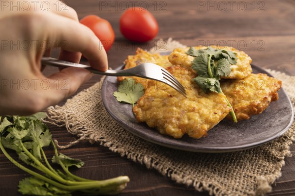 Fried crispy Chicken pancakes with hand on brown wooden background and linen textile. side view, close up, selective focus