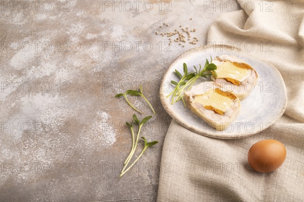 Chicken, egg and dried apricot meatloaf, microgreen on brown concrete background and linen textile. side view, copy space