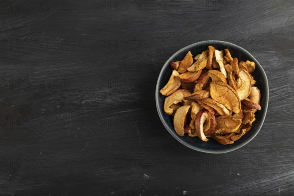 Dried Apples in ceramic bowl on black wooden background. Top view, copy space, flat lay. healthy food, minimalism. sweet