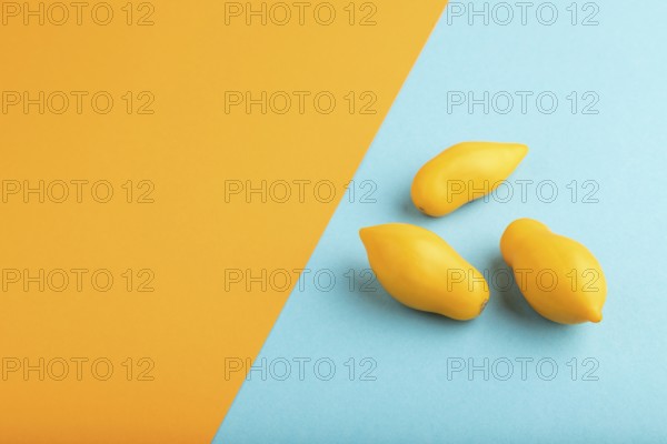 Yellow tomatoes on blue and orange pastel paper background. Side view, copy space. healthy food, vegetable, minimalism