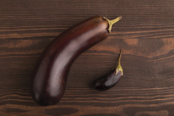 Two Eggplants big and small on brown wooden background, top view, flat lay, copy space, minimalism
