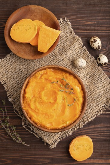 Sweet potato porridge in wooden bowl on wooden background and linen textile. Diet, healthy eating concept. top view, flat lay, close up, minimalism