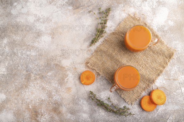 Two glasses with carrot juice, on brown concrete background and linen textile. Diet, healthy eating concept. top view, flat lay, copy space, minimalism