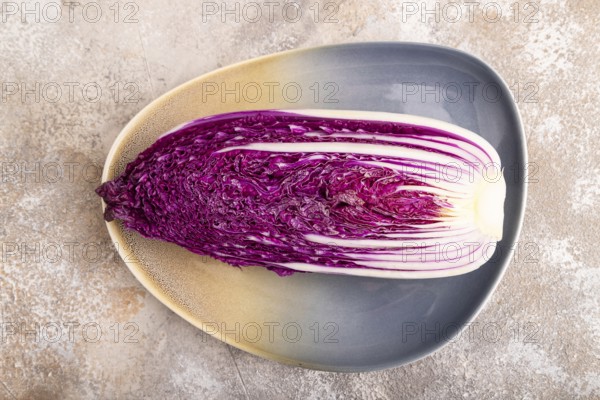Purple Chinese cabbage on blue plate on brown concrete background, top view, flat lay, close up, minimalism