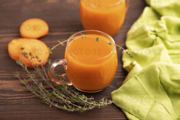 Two glasses with carrot juice, on wooden background and green textile. Diet, healthy eating concept. side view, close up, minimalism, selective focus