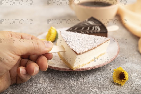 Chocolate and Vanilla Cake pops Marshmallow with hand with cup of coffee on brown concrete background and orange linen textile. side view, close up, selective focus hold