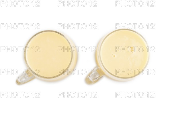 Organic non dairy banana and soy milk in glass isolated on white background. Vegan healthy food concept, flat lay, top view, close up