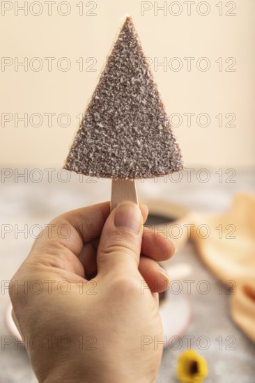 Chocolate and Vanilla Cake pops Marshmallow with hand with cup of coffee on brown concrete background and orange linen textile. side view, close up, selective focus hold