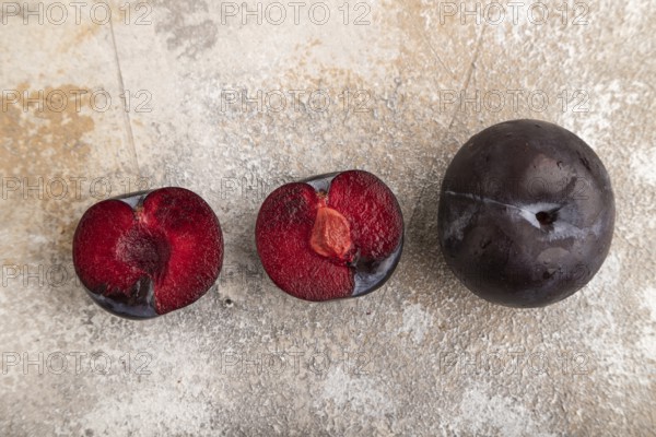 Purple Plum Cut in half on brown concrete background. Top view, flat lay, copy space. healthy food, vegetable, minimalism