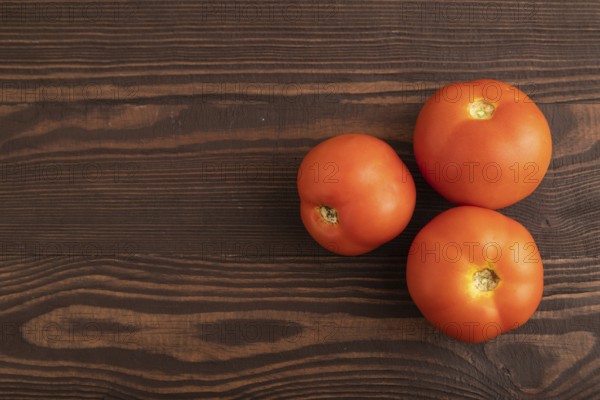 Red tomato on brown wooden background. Top view, flat lay, copy space. healthy food, vegetable, minimalism