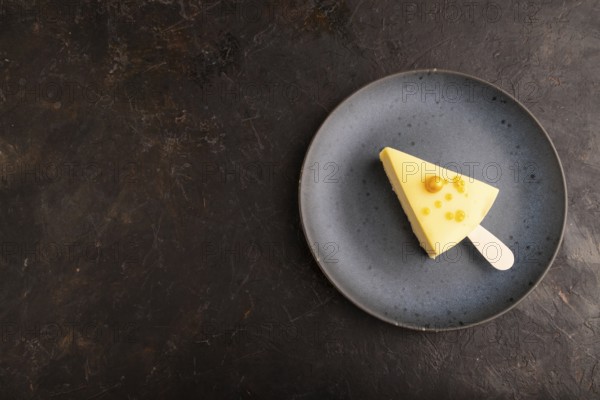 Yellow Cake pop with sprinkles on blue ceramic plate on black concrete background, top view, flat lay, copy space, minimalism