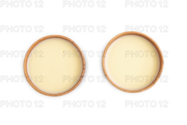 Organic non dairy banana and soy milk in clay cup isolated on white background. Vegan healthy food concept, flat lay, top view, close up