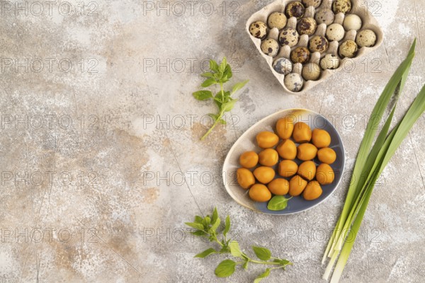 Pile of Smoked Quail eggs on plate on a brown concrete background. top view, flat lay, copy space