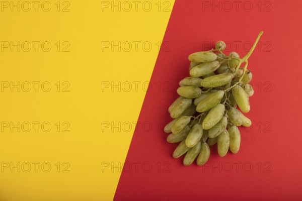 Green grapes on yellow and red paper pastel background. Top view, flat lay, copy space. healthy food, minimalism