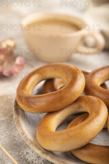Homemade Ring Bagel with cup of coffee on brown concrete background and linen textile. side view, close up, selective focus