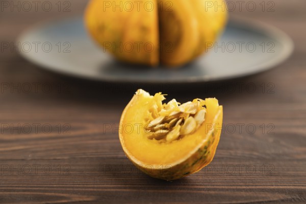 Orange Pumpkin cutted on blue plate on brown wooden background. Side view, copy space, healthy food, vegetable, minimalism, contrast