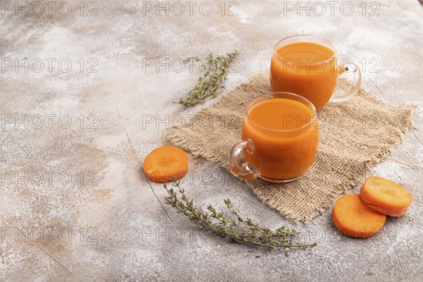 Two glasses with carrot juice, on brown concrete background and linen textile. Diet, healthy eating concept. side view, copy space, minimalism