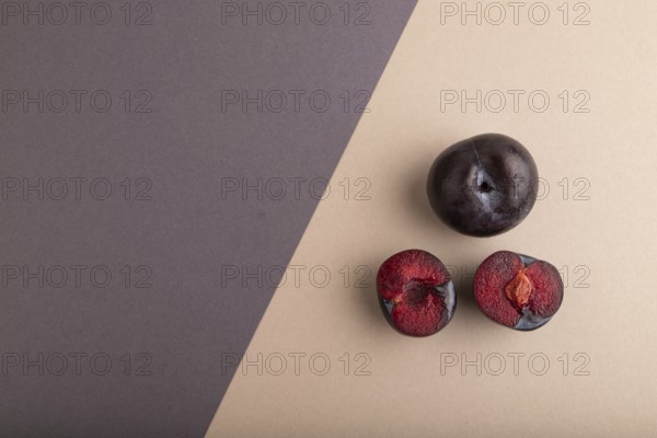 Purple Plum Cut in half on beige and gray pastel paper background. Top view, flat lay, copy space. healthy food, vegetable, minimalism