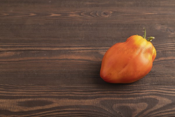 Red Heart Shape tomato on brown wooden background. Side view, copy space. healthy food, vegetable, minimalism