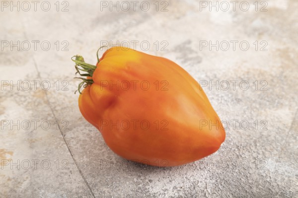 Red Heart Shape tomato on brown concrete background. Side view, close up. healthy food, vegetable, minimalism