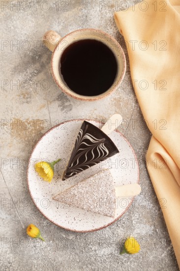 Chocolate and Vanilla Cake pops Marshmallow with cup of coffee on brown concrete background and orange linen textile. top view, flat lay, copy space