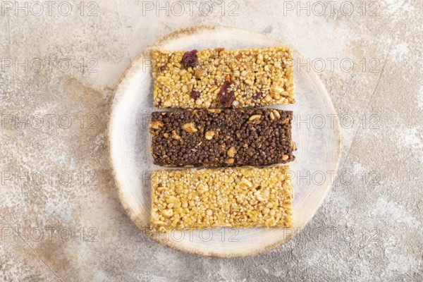 Granola bars with caramel, nuts, flakes in ceramic plate on brown concrete background. Top view, flat lay, copy space