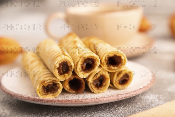 Waffles with caramel on brown concrete background and orange linen textile, cup of coffee, side view, close up, selective focus