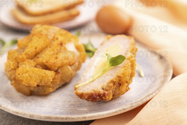Chicken Schnitzel on blue plate with microgreen on brown concrete background and orange linen textile. side view, close up, selective focus