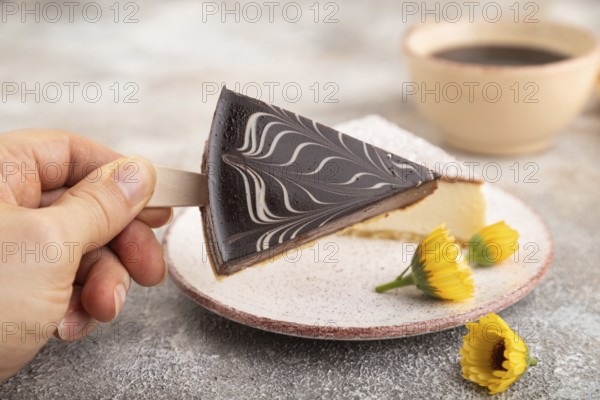 Chocolate and Vanilla Cake pops Marshmallow with hand with cup of coffee on brown concrete background and orange linen textile. side view, close up, selective focus hold