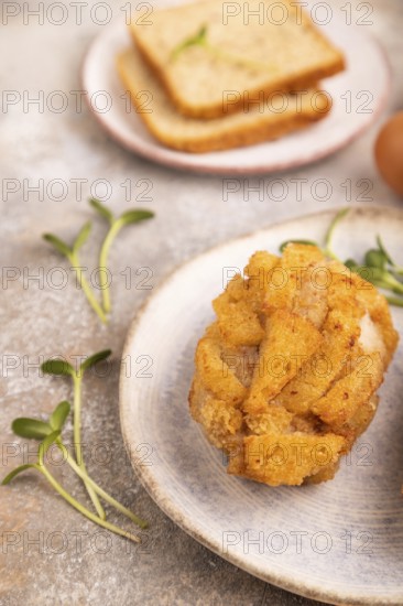 Chicken Schnitzel on blue plate with microgreen on brown concrete background and orange linen textile. side view, close up, selective focus