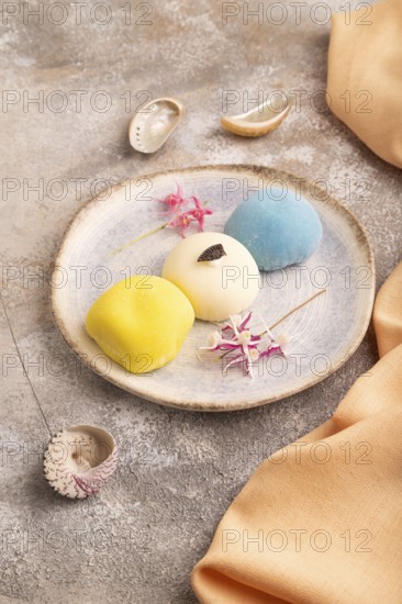 Japanese Mochi Cakes on brown concrete background and orange textile, side view, close up