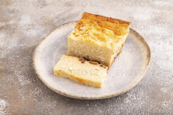 ?ottage cheese ?asserole, Curd cake, with dried apricots and raisins on brown concrete background, side view, close up, minimalism