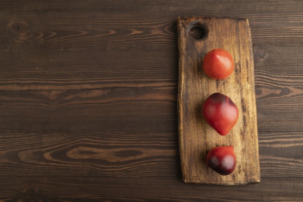 Yellow tomatoes on cutting board on brown wooden background. Top view, copy space, flat lay. healthy food, vegetable, minimalism