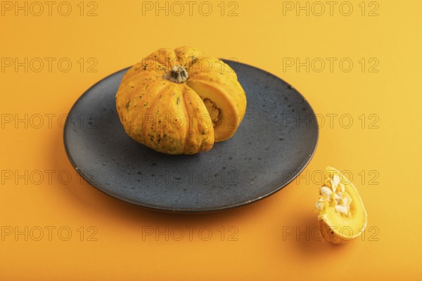 Orange Pumpkin cutted on blue plate on orange pastel paper background. Side view, copy space, healthy food, vegetable, minimalism, contrast
