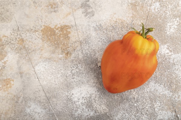 Red Heart Shape tomato on brown concrete background. Top view, flat lay, copy space. healthy food, vegetable, minimalism