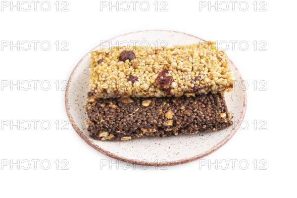 Granola bars with caramel, nuts, flakes in ceramic plate isolated on white background. Side view, close up