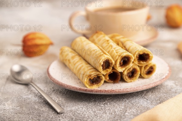 Waffles with caramel on brown concrete background and orange linen textile, cup of coffee, side view, close up, selective focus