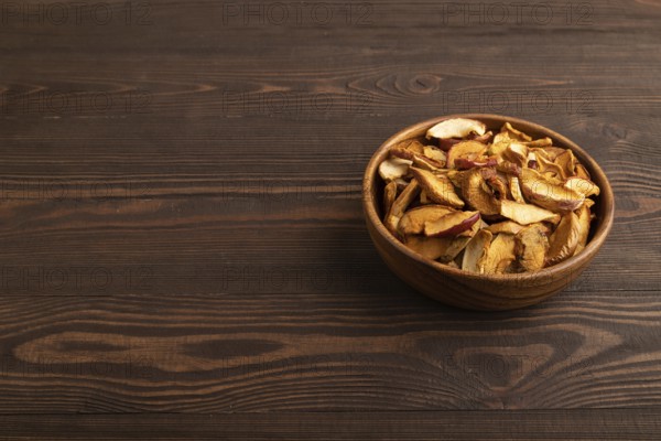 Dried Apples in wooden bowl on brown wooden background. Side view, copy space, healthy food, minimalism. sweet