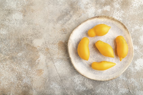 Yellow tomatoes on plate on brown concrete background. Top view, copy space, flat lay. healthy food, vegetable, minimalism