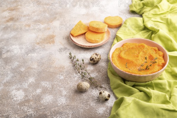 Sweet potato porridge in ceramic bowl on brown concrete background and green textile. Diet, healthy eating concept. side view, copy space