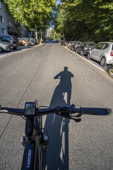 Cycling in the city, city centre street, shadow of the biker, cyclist perspective, Essen, North Rhine-Westphalia, Germany