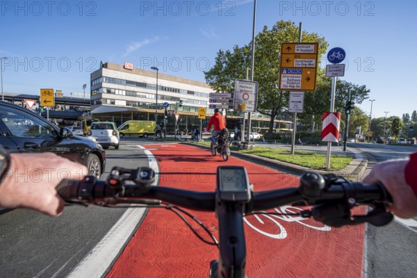 Riding a bike in a bike lane, marked in red to attract the attention of motorists, between 2 lanes, Huyssenallee, in front of Europaplatz, in the city centre of Essen, North Rhine-Westphalia, Germany